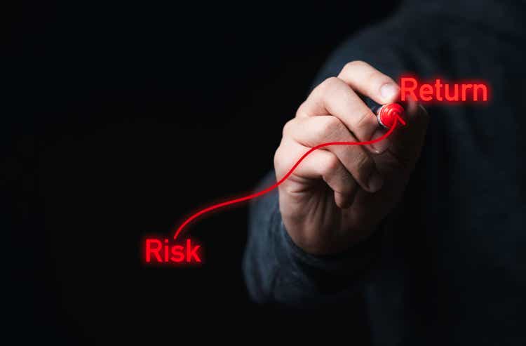 Businessman drawing red arrow and risk return wording, Investment relation between high low and risk return concept.