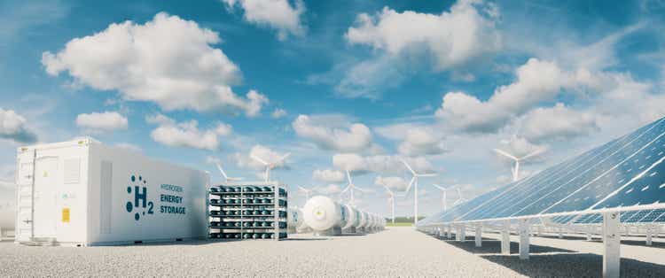 Modern hydrogen energy storage system accompaind by large solar power plant and wind turbine park in sunny summer afteroon light with blue sky and scattered clouds. 3d rendering.