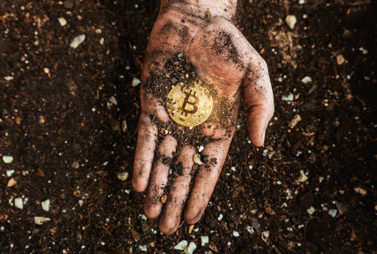 A golden bitcoin on the dirty hand of a miner.  Metaphor for mining BTC and cryptocurrencies.  Digital business and decentralized economy concept