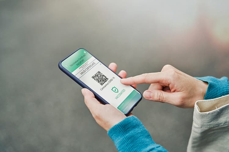 Mid adult woman using a Digital vaccine passport with smart phone in outdoor.