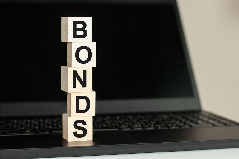 BONDS word made with building blocks on the black keyboard. A row of wooden cubes with a word written in black font is located on a black keyboard.