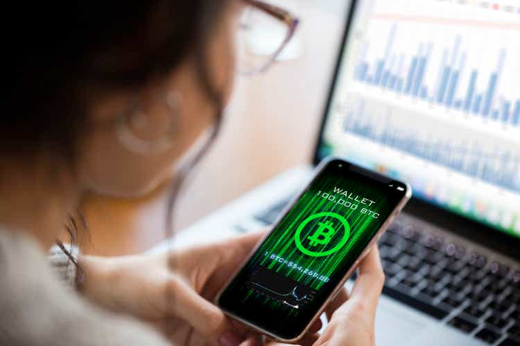 Young woman using cryptocurrency application on smartphone