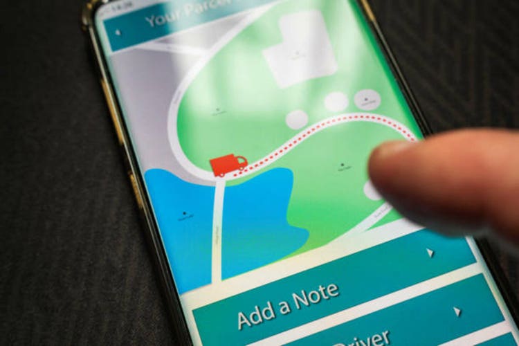 Male thumb finger over parcel delivery app on smartphone screen