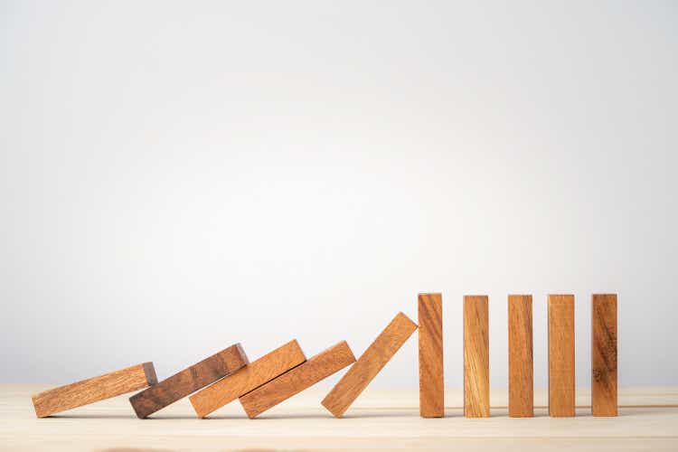 Many wooden block dominoes falling on one wooden block, resist and stop risk management concept.