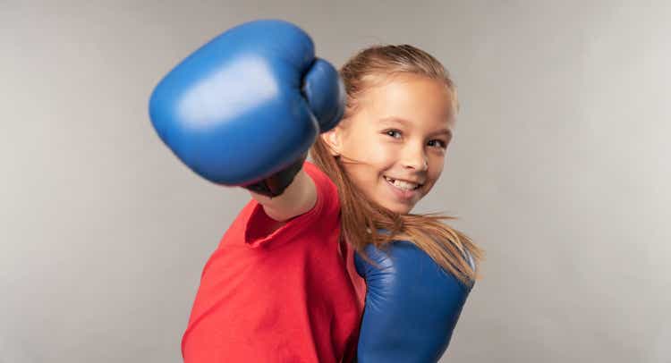 Adorable little girl boxer practicing punches in studio