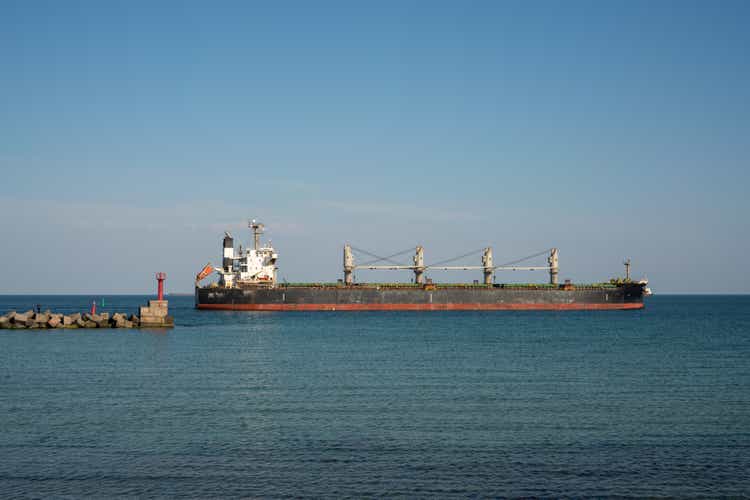 A large dry cargo ship leaves the port past the breakwater.