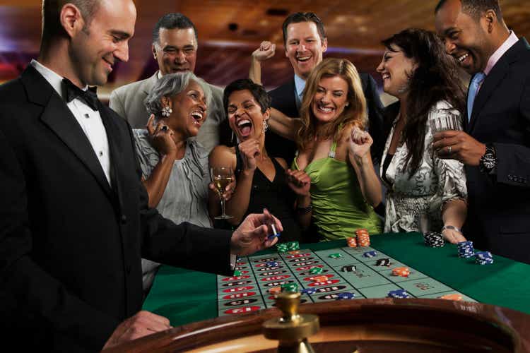 Excited friends gambling at roulette table in casino