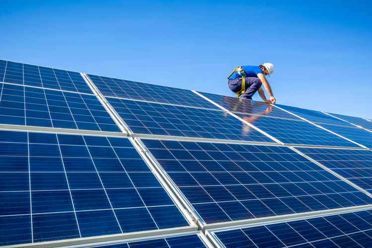 Solar panel installer installing solar panels on roof of modern house