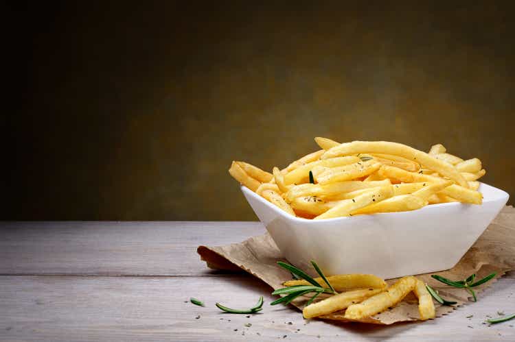 French fries and fresh rosemary on wooden table, copy space.