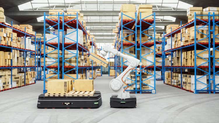 Automated Robot Carriers And Robotic Arm In Modern Distribution Warehouse