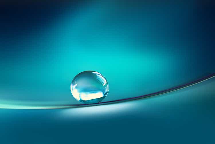 Beautiful transparent drop of water on smooth surface in dark blue colors.