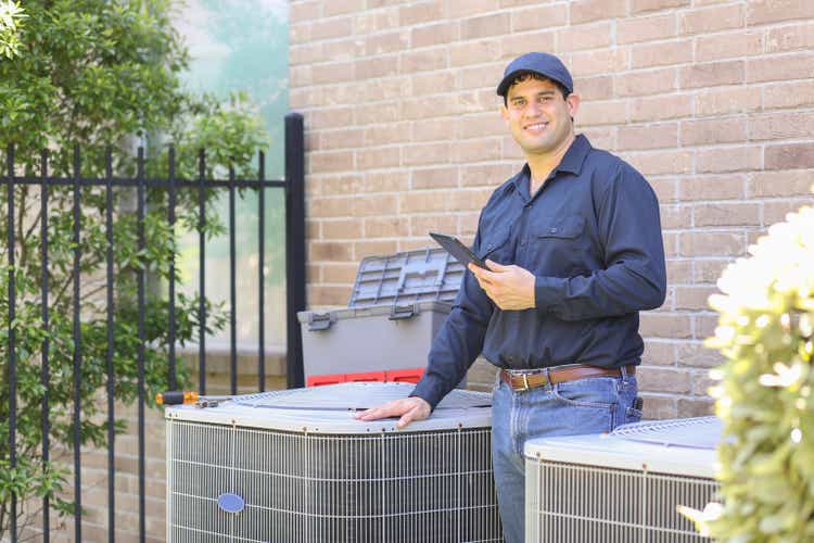 Latin descent, blue collar air conditioner repairman at work.