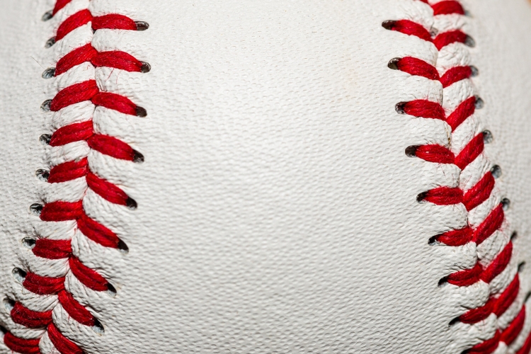 A macro of a baseball with red stitching and room for copy on the ball