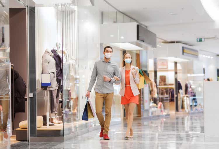 couple in medical masks with shopping bags in mall