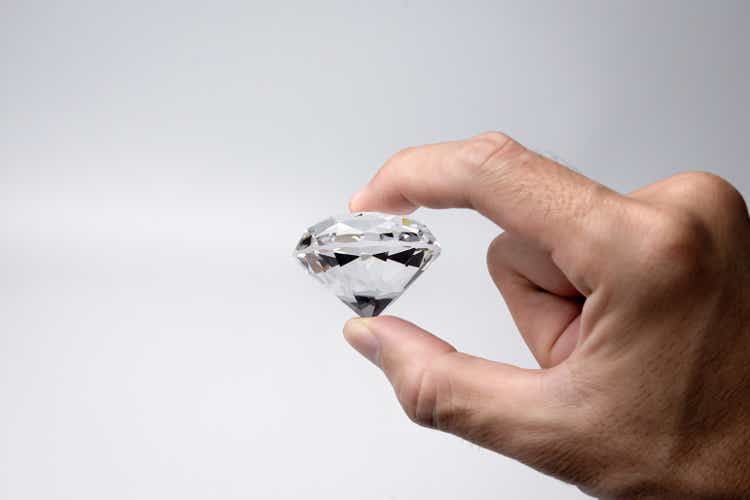 Close-up of the hand with large size round cut diamond on white background.