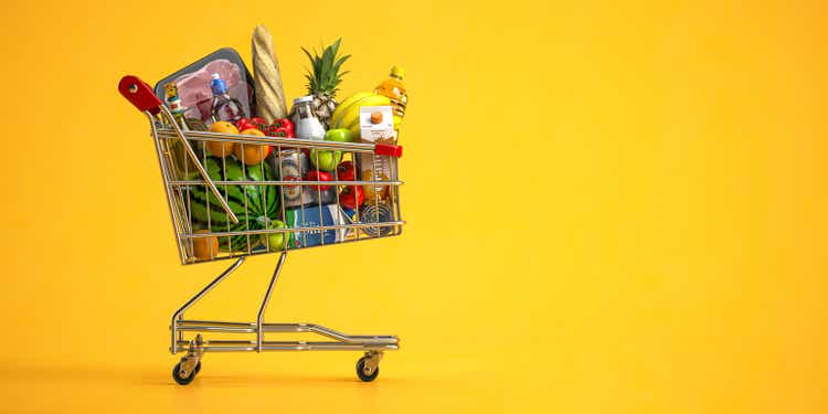 Einkaufswagen voller Lebensmittel auf gelbem Hintergrund. Lebensmittel- und Lebensmittelgeschäft-Konzept.
