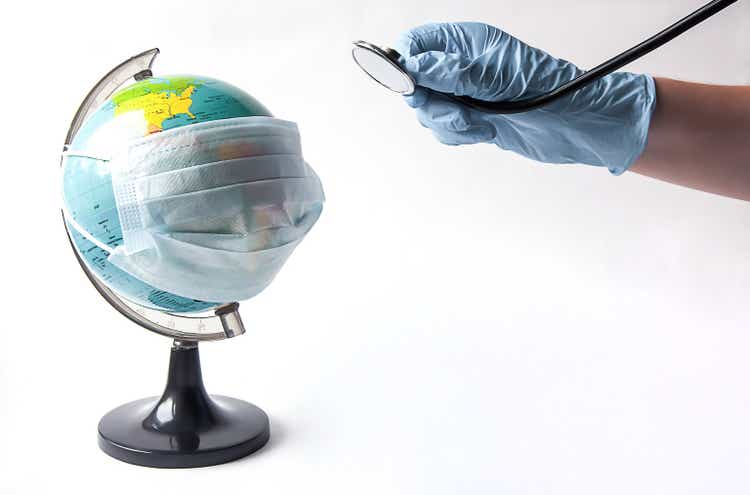 Een bol in een masker en een hand met een stethoscoop. Behandeling van de hele wereld.