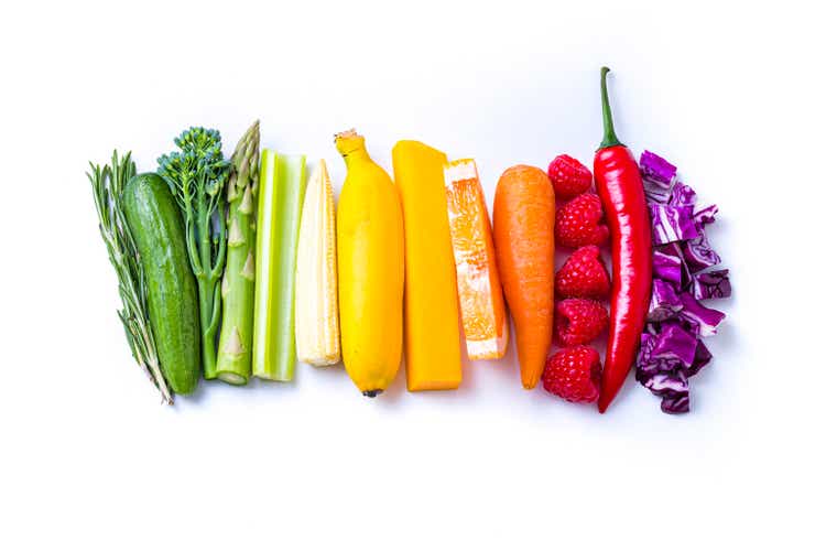 Duhová barevná zelenina a ovoce se drží na bílém pozadí