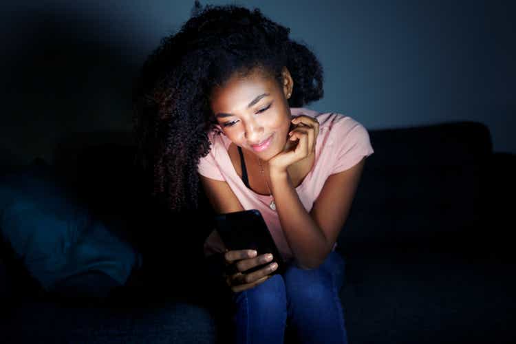 Young black woman texting on mobile phone at night