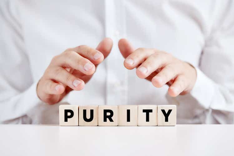 A man holding his hands over the wooden cubes with the word purity.