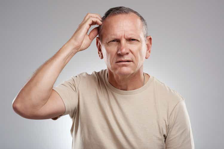 Shot of a handsome mature man standing against a grey background in the studio and scratching his head in confusion