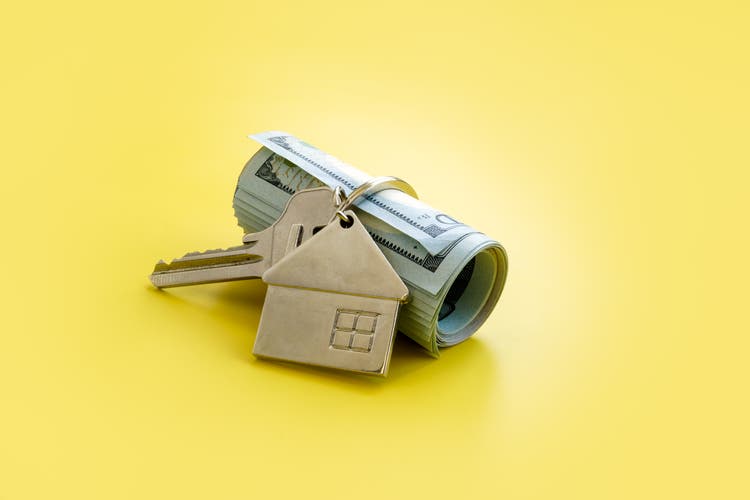 Roll of cash and key with home. Money for rent or mortgage.