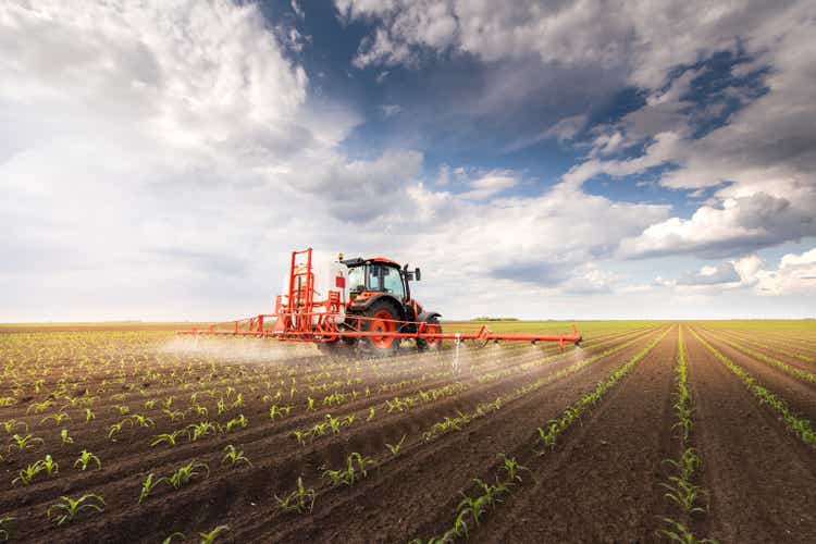 Tractor spraying pesticides on corn field with sprayer at spring