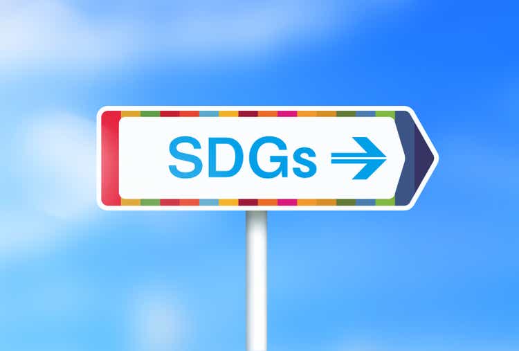 Image of a sign saying "SDGs" with a background of fresh greenery and clouds