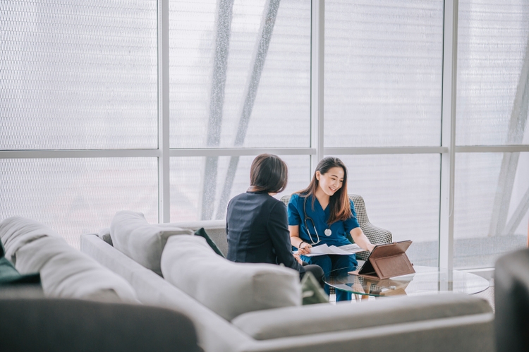 Asian chinese female doctor explaining medical report To a female Patient at her office sofa