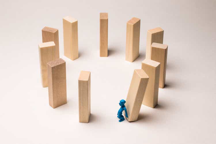 A toy man pushes a wooden block. The beginning of a fatal series of events. At some future point, everyone will still have to pay for their mistakes. Karma, concept.