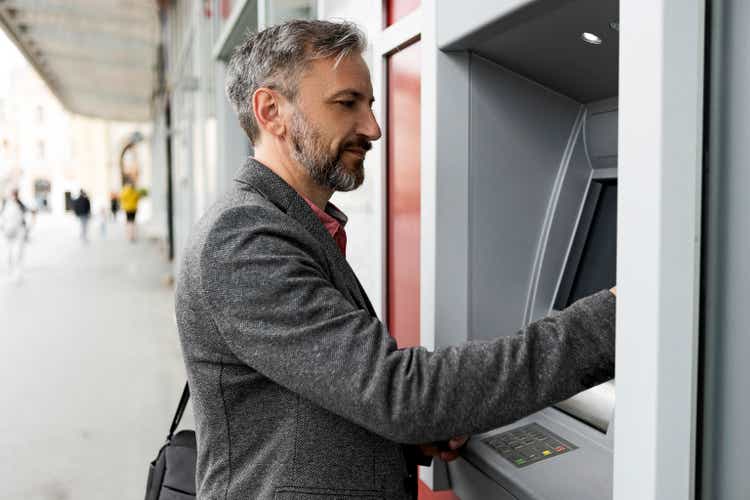 Businessman using card at an ATM in city