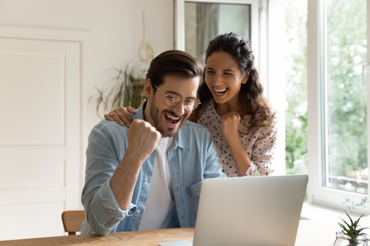 Overjoyed loving young couple celebrating online success.