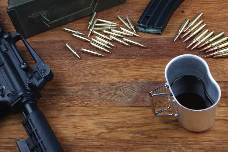 rifle, ammunitions and cup of coffee on wooden table
