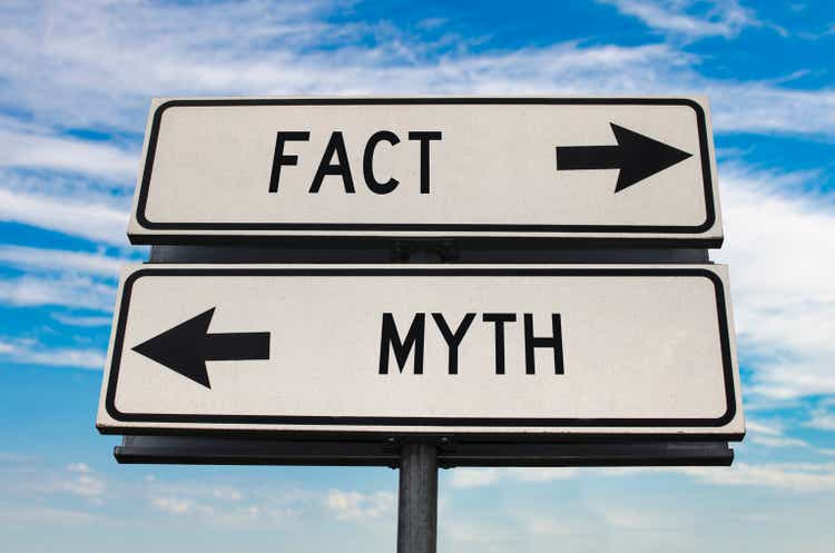 Fact versus myth road sign with two arrows on blue sky background. White two street sign with arrows on metal pole. Two way road sign with text.