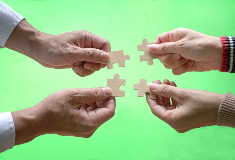 Business people assembling jigzaw puzzle. Close up shot.