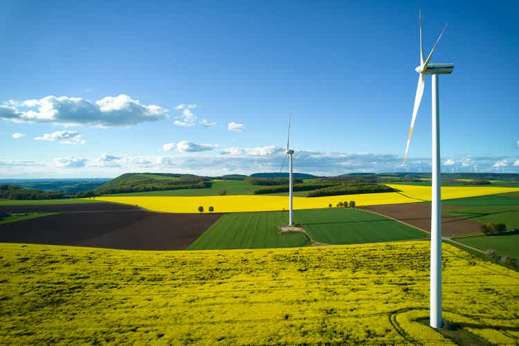 2 Vestas Windkraftanlagen im Rap-Feld. Landwirtschaftliche Fläche mit blauem Himmel. Luftbild. Seitenansicht.