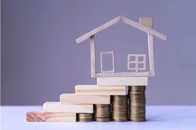 Small model house on the stairs money coin with white background. Concept of saving to housing, loan to buy a house.