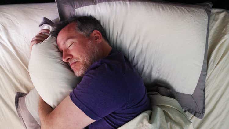 Mature man in bed hugging his pillow with a satisfied expression