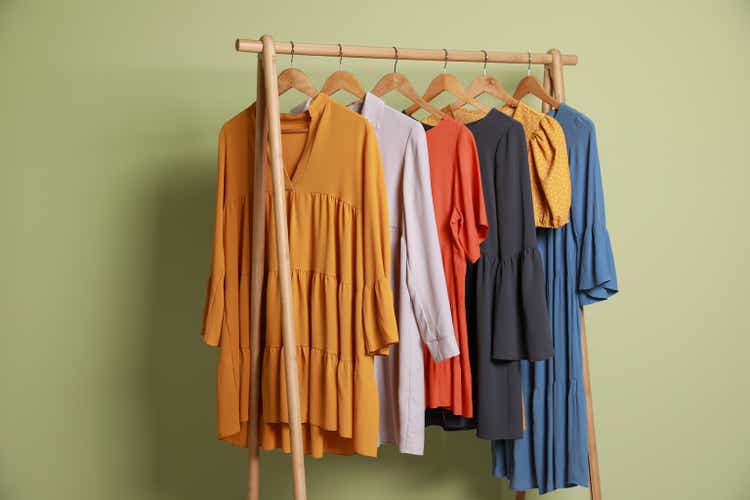 Collection of trendy women"s garments on rack near green wall. Clothing rental service