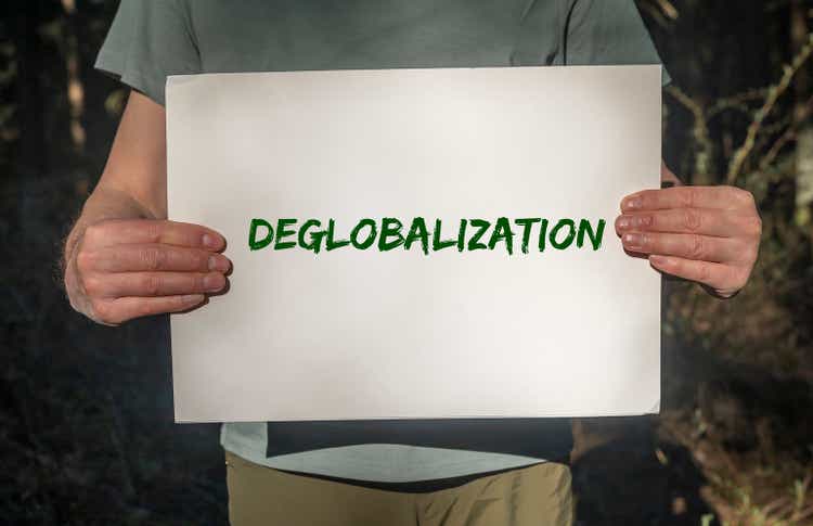Deglobalization and reverse globalization concept. Word on paper placard in male hands with forest background