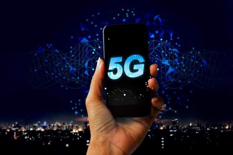 5G network digital hologram and internet of things on city background - Hand holding mobile phone concept of future technology 5G network