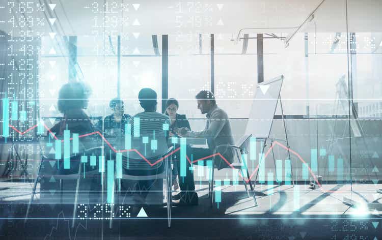 Digitally enhanced shot of a group of businesspeople meeting in the boardroom superimposed over a graph showing the ups and downs of the stock market