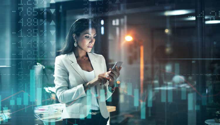 Digitally enhanced shot of an attractive businesswoman using a cellphone superimposed over a graph showing the ups and downs of the stock market