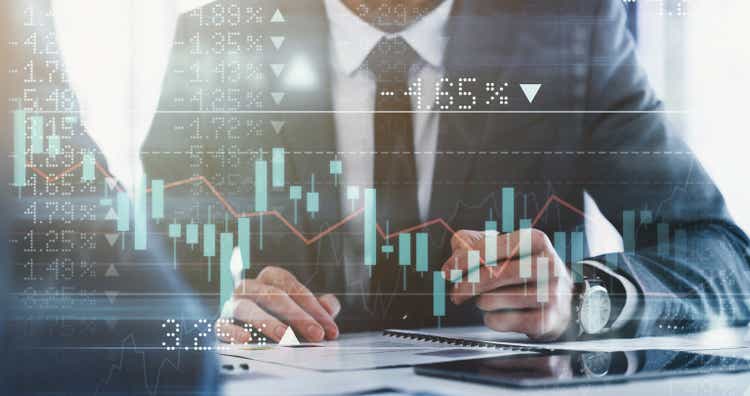 Digitally enhanced shot of a group of unrecognizable businesspeople meeting in the boardroom superimposed over a graph showing the ups and downs of the stock market