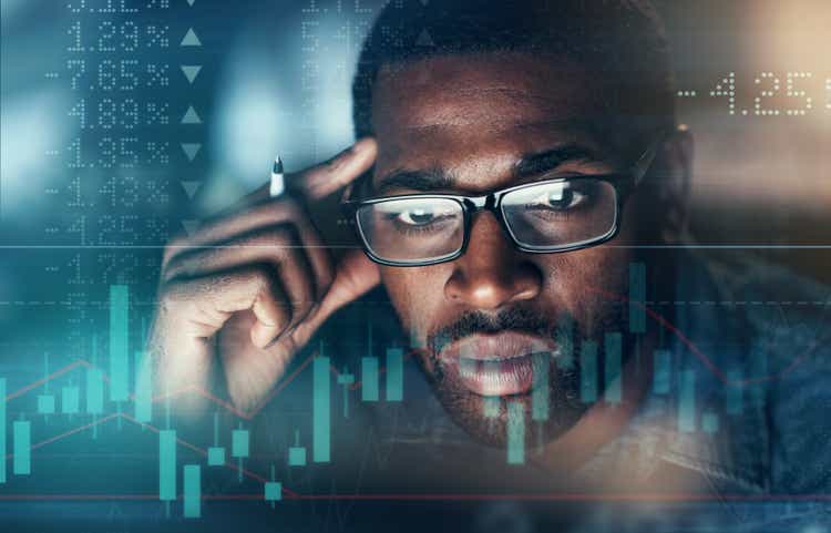 Digitally enhanced shot of an unrecognizable businessman working in the office superimposed over a graph showing the ups and downs of the stock market