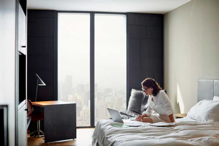Businesswoman using laptop on bed in hotel room
