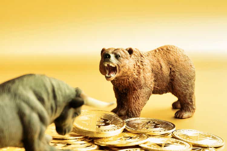 Bear and bull fighting over bitcoins against golden background. Market trend concept.