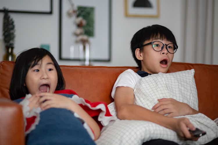 Asian Chinese sibling watching scary movie on television together at their home