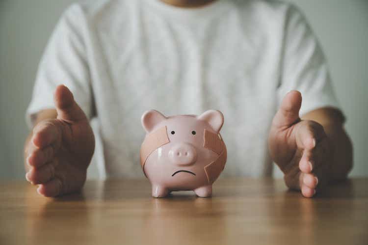 Man hand protect piggy bank on wood table. Save money and financial investment