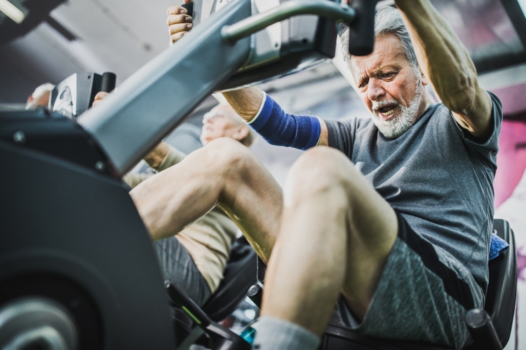 Below view of determined mature man exercising on stationary bike in a gym.